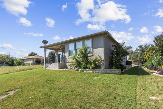 back of house with a lawn and ceiling fan