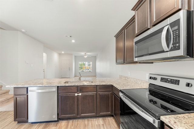 kitchen featuring sink, light wood-type flooring, dark brown cabinets, kitchen peninsula, and stainless steel appliances