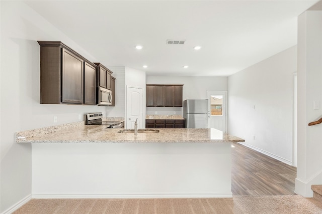 kitchen featuring sink, dark brown cabinets, kitchen peninsula, light hardwood / wood-style floors, and stainless steel appliances