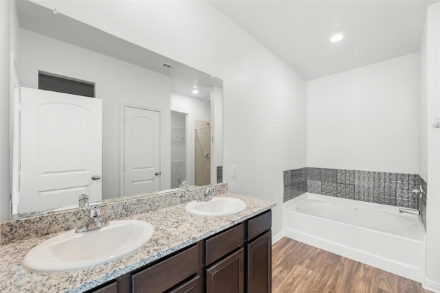 bathroom featuring vanity, a tub to relax in, and wood-type flooring