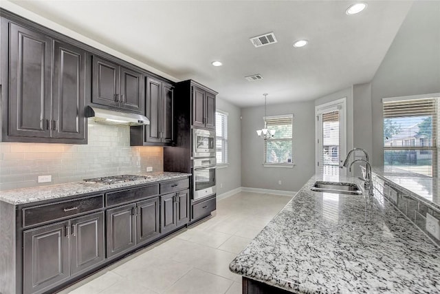 3317 Venezia Vw, Leander, TX 78641 - kitchen with appliances with stainless steel finishes, baseboards, a sink, under cabinet range hood, and decorative backsplash