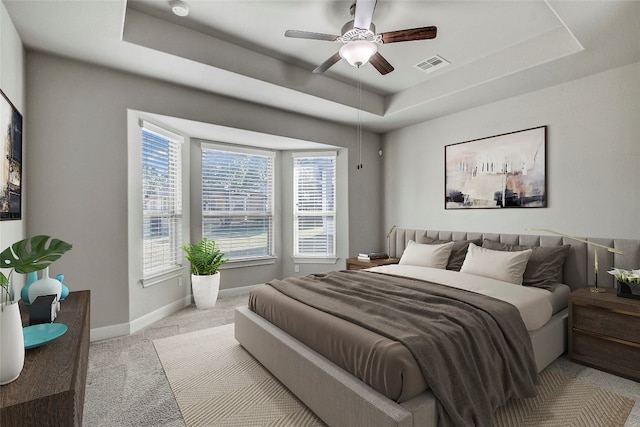 carpeted bedroom with a tray ceiling and ceiling fan