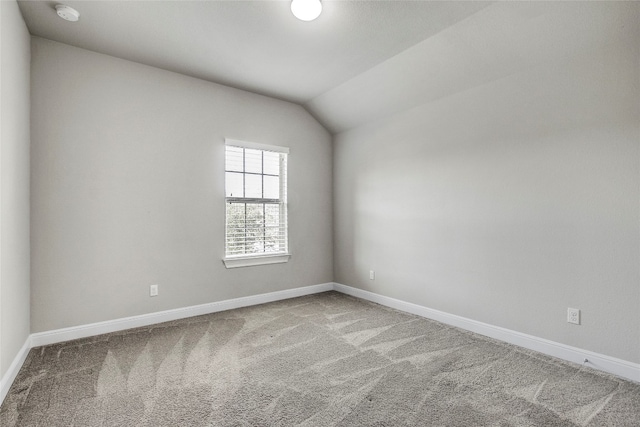 spare room featuring carpet and vaulted ceiling