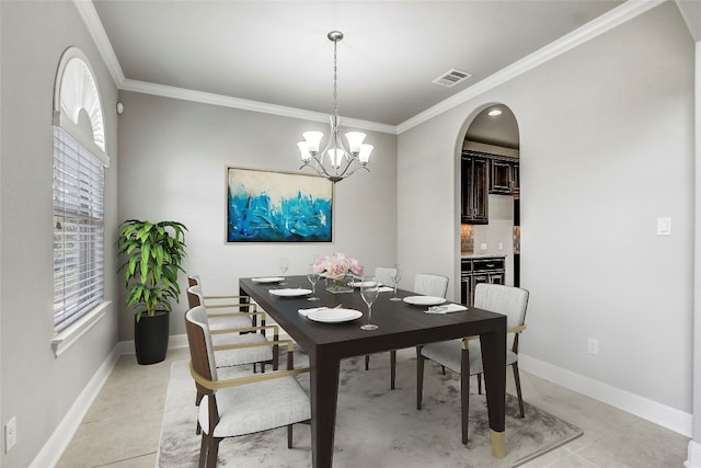 dining area with light tile patterned flooring, ornamental molding, and an inviting chandelier