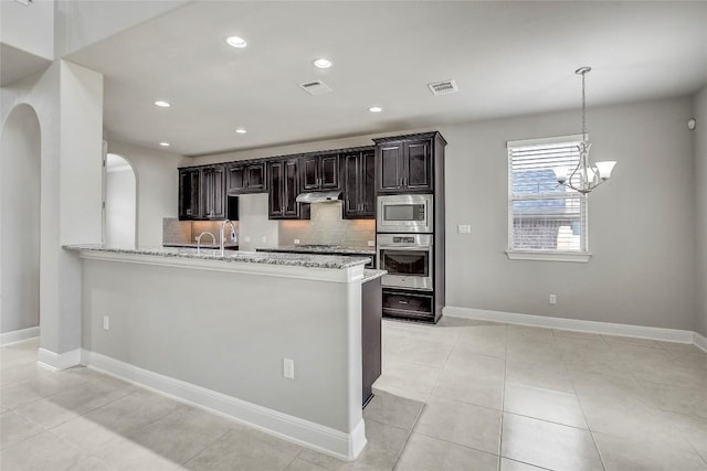 3317 Venezia Vw, Leander, TX 78641 - kitchen with stainless steel appliances, decorative backsplash, under cabinet range hood, light stone countertops, and baseboards