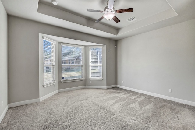 unfurnished room with a tray ceiling, ceiling fan, and light colored carpet