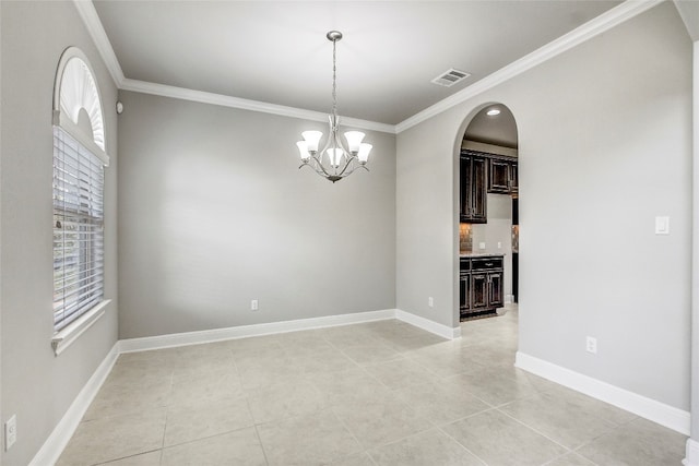 tiled spare room featuring crown molding and a notable chandelier