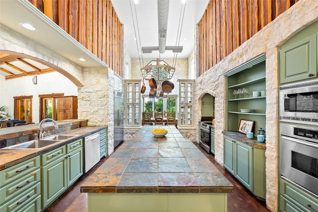 kitchen with green cabinetry, a high ceiling, and built in appliances