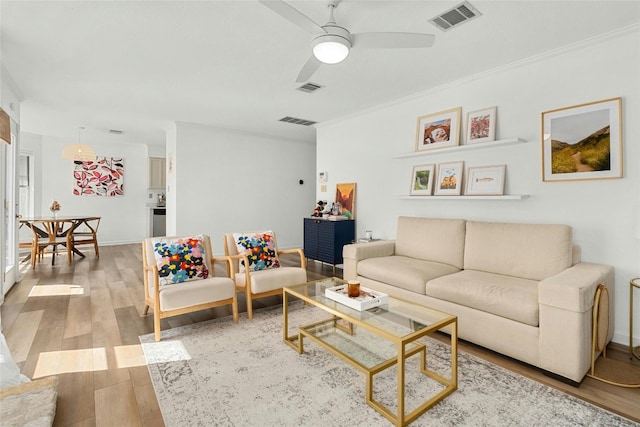 living room featuring ceiling fan, ornamental molding, and hardwood / wood-style flooring