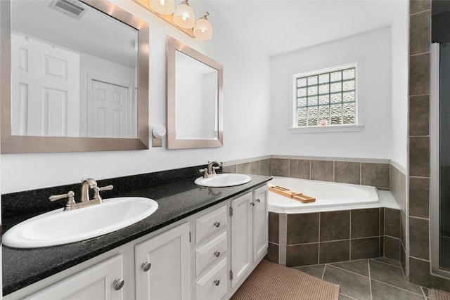 bathroom featuring tile patterned flooring, vanity, and a relaxing tiled tub