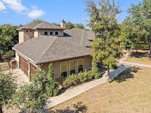 view of front of property featuring a front lawn, a chimney, a shingled roof, and stucco siding