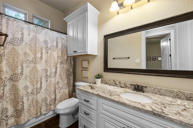 full bath with toilet, a shower with shower curtain, wood finished floors, and vanity