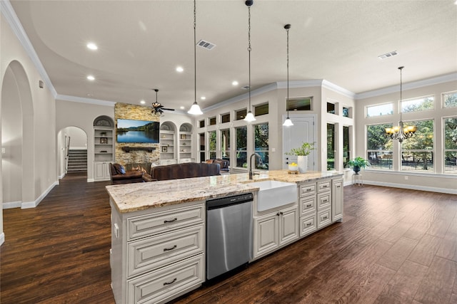 kitchen featuring an island with sink, sink, stainless steel dishwasher, a stone fireplace, and dark hardwood / wood-style floors