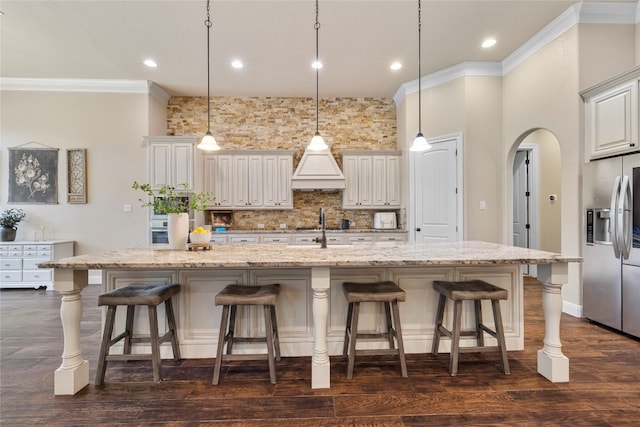 kitchen with dark hardwood / wood-style flooring, hanging light fixtures, a large island with sink, and a breakfast bar