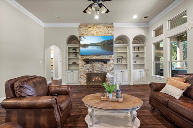 living room with ceiling fan, built in features, a fireplace, crown molding, and dark hardwood / wood-style flooring