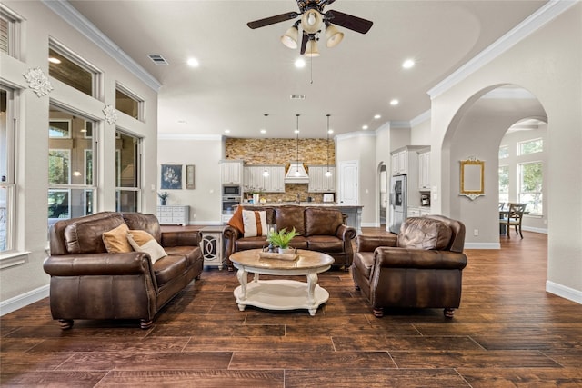 living area featuring dark wood-type flooring, arched walkways, visible vents, and crown molding