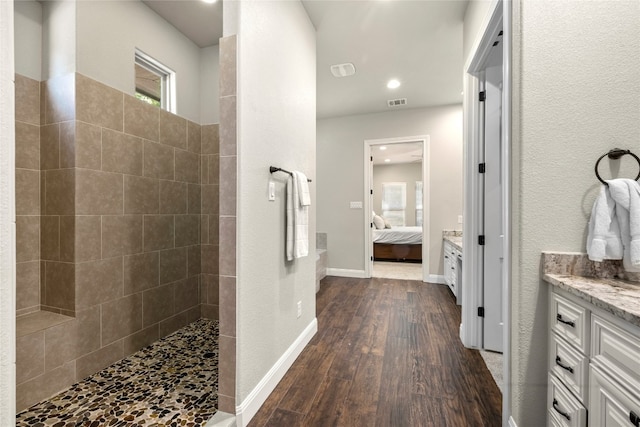 full bath with baseboards, ensuite bath, wood finished floors, walk in shower, and vanity