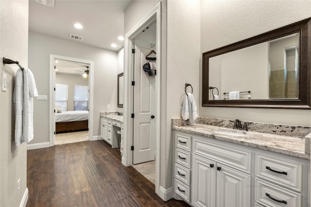 ensuite bathroom featuring baseboards, visible vents, connected bathroom, wood finished floors, and vanity