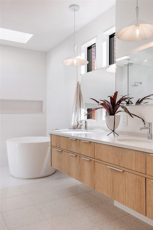 2112 Lawnmont Ave, Austin, TX 78756 - bathroom featuring double vanity, speckle patterned floor, a soaking tub, and a skylight