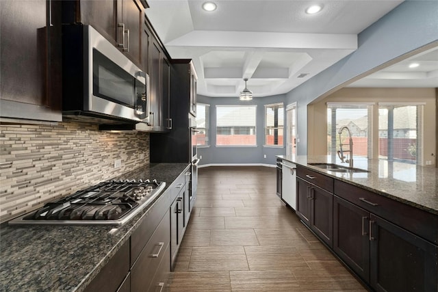 kitchen with dark stone countertops, appliances with stainless steel finishes, sink, and a wealth of natural light