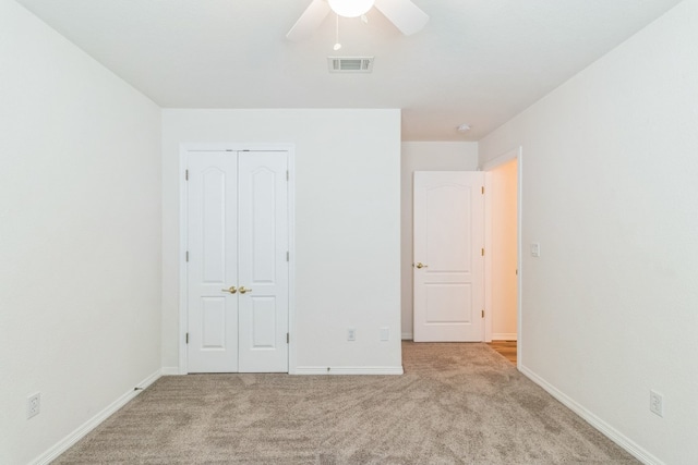 unfurnished bedroom with a closet, light colored carpet, and ceiling fan