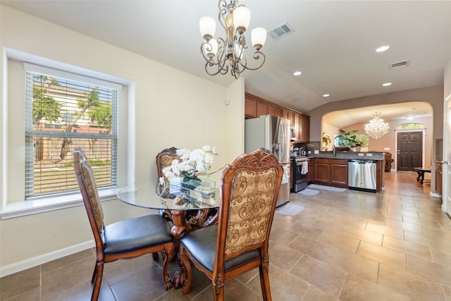 dining space featuring vaulted ceiling, an inviting chandelier, and sink