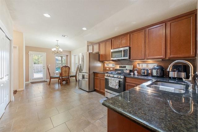 kitchen with decorative backsplash, stainless steel appliances, sink, pendant lighting, and a notable chandelier