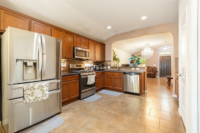 kitchen with sink, kitchen peninsula, vaulted ceiling, an inviting chandelier, and appliances with stainless steel finishes