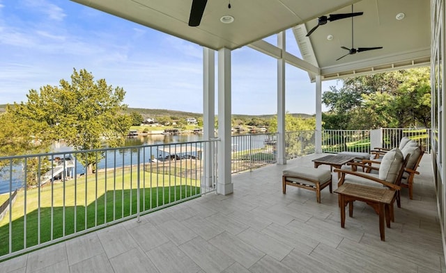 sunroom featuring ceiling fan, a water view, and vaulted ceiling