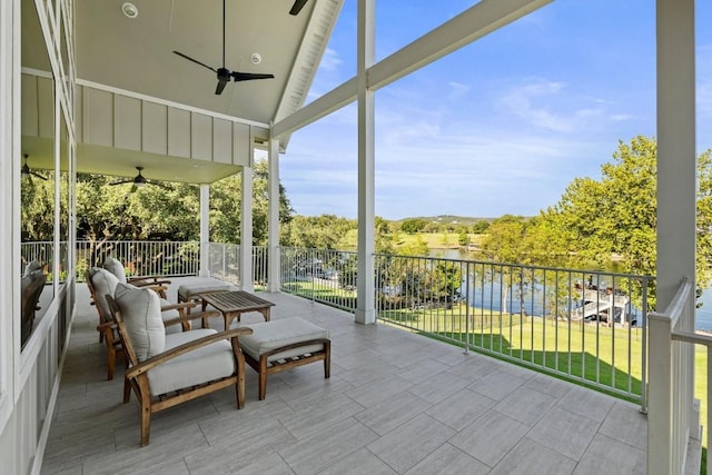 sunroom with ceiling fan, a water view, and vaulted ceiling