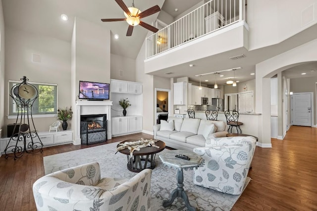 living room with dark hardwood / wood-style flooring, high vaulted ceiling, and ceiling fan