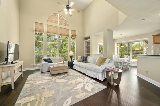 living room featuring a high ceiling, ceiling fan, and dark wood-type flooring