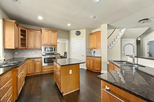 kitchen with sink, stainless steel appliances, dark hardwood / wood-style floors, and an island with sink