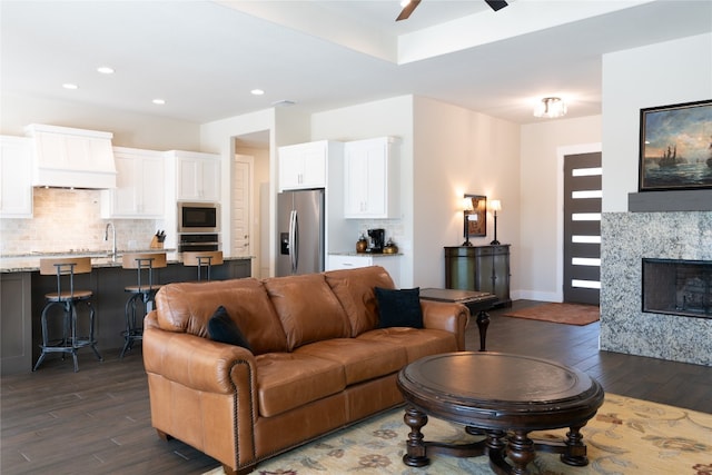 living room featuring a fireplace, ceiling fan, sink, and dark hardwood / wood-style flooring