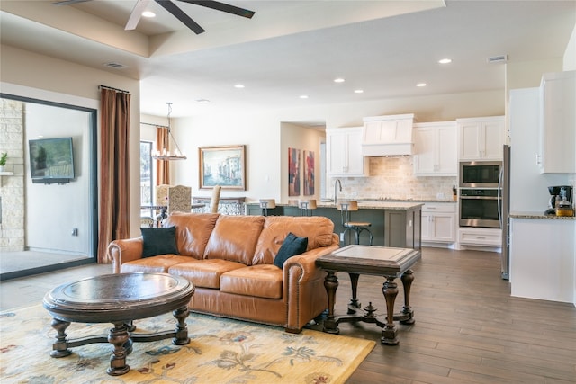 living room with ceiling fan with notable chandelier and dark hardwood / wood-style flooring