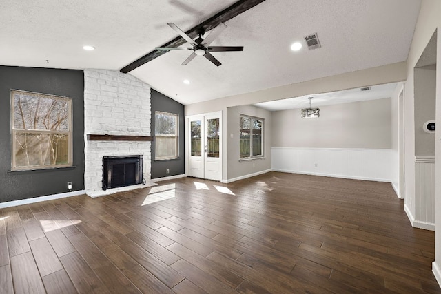 4910 Pelham Dr, Austin, TX 78727 - unfurnished living room with a ceiling fan, wainscoting, a stone fireplace, wood finished floors, and a textured ceiling