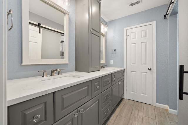 4910 Pelham Dr, Austin, TX 78727 - bathroom featuring double vanity, wood finish floors, and a textured wall