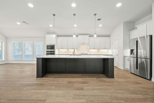 kitchen with stainless steel appliances, decorative light fixtures, vaulted ceiling, and white cabinetry