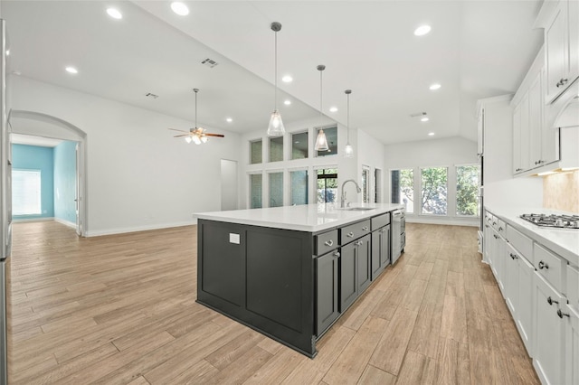 kitchen featuring white cabinets, pendant lighting, sink, a center island with sink, and light hardwood / wood-style floors