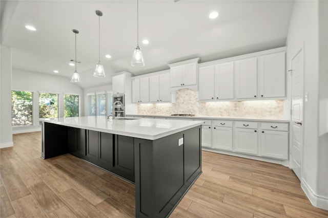 kitchen with a spacious island, white cabinets, and light hardwood / wood-style floors