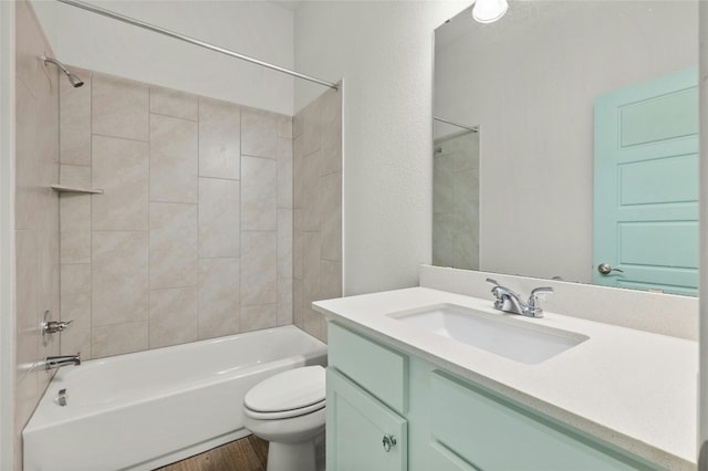 full bathroom featuring wood-type flooring, vanity, tiled shower / bath combo, and toilet