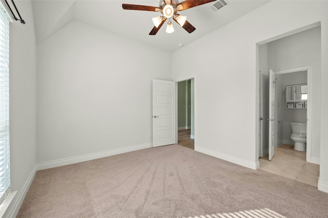 unfurnished bedroom with multiple windows, ceiling fan, vaulted ceiling, and light colored carpet