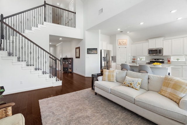 living room with a high ceiling and dark wood-type flooring