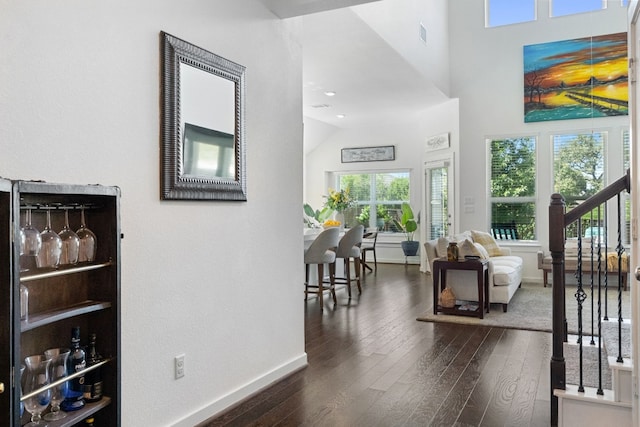 interior space featuring dark wood-type flooring, a towering ceiling, baseboards, and stairs