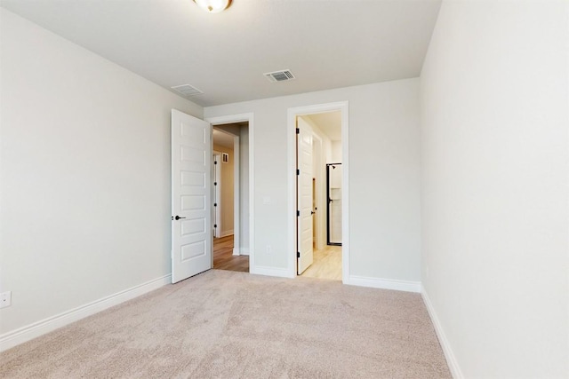 unfurnished bedroom with light carpet and white refrigerator