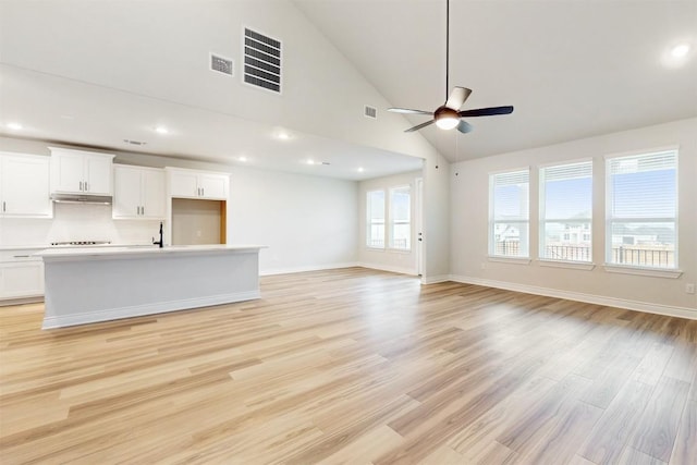 unfurnished living room with light wood-type flooring, high vaulted ceiling, ceiling fan, and sink