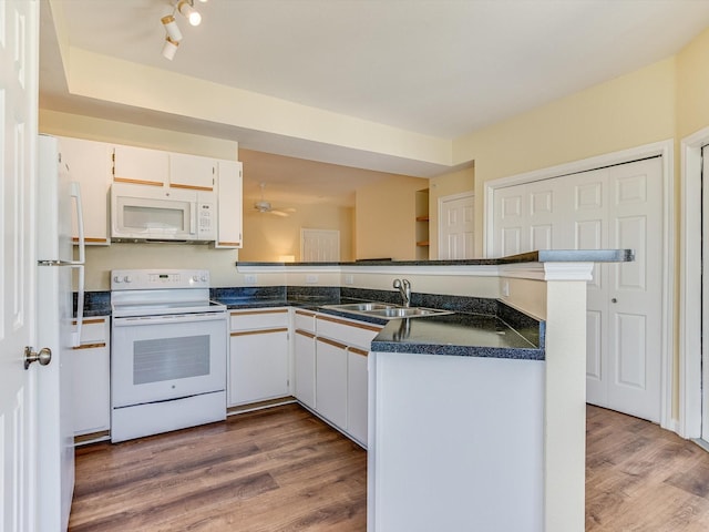 kitchen featuring sink, white cabinets, white appliances, hardwood / wood-style floors, and kitchen peninsula