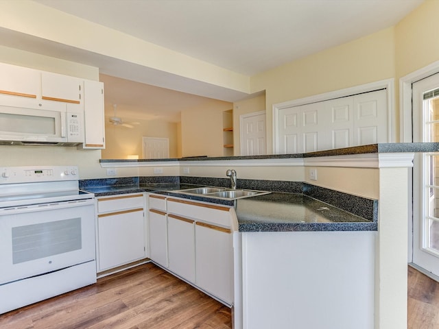 kitchen with white appliances, kitchen peninsula, light hardwood / wood-style flooring, white cabinetry, and sink