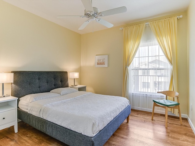 bedroom with hardwood / wood-style floors, ceiling fan, and multiple windows