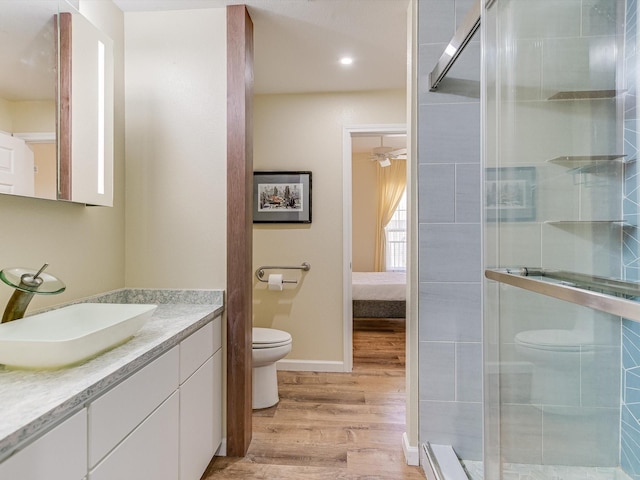 bathroom with toilet, a shower with shower door, wood-type flooring, and vanity